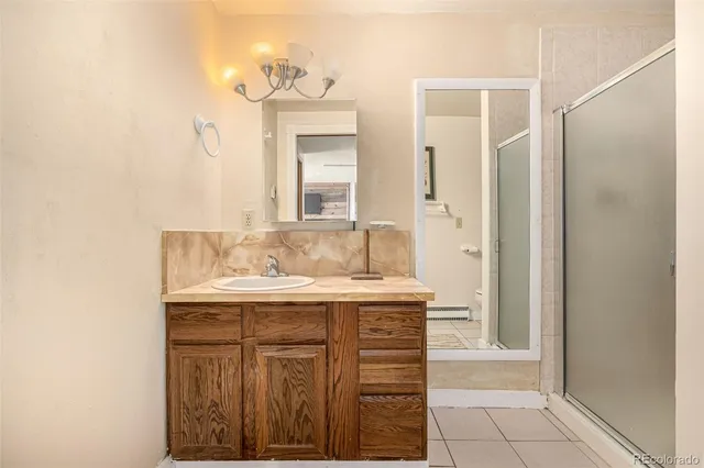 a bathroom with a granite countertop sink a mirror and a shower