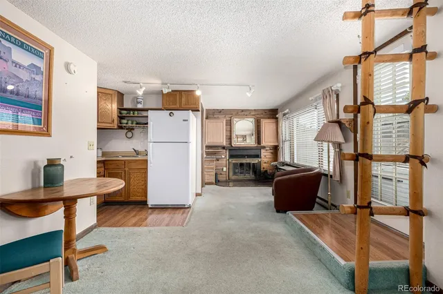 a room with furniture a refrigerator and a view of kitchen