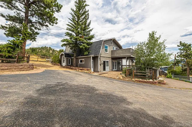 a view of a house with wooden fence and large trees