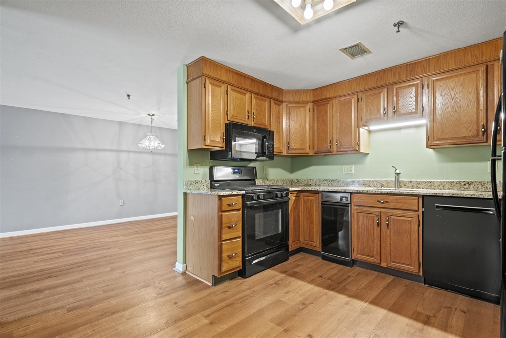 45 Christopher Drive, Unit 101 Methuen, MA 01844 - Photo 9 of 32 a kitchen with granite countertop wooden cabinets a stove top oven a granite counter space and a window