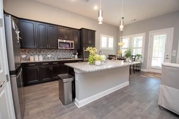 a kitchen with kitchen island granite countertop wooden cabinets a counter top space and a sink