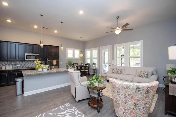 a living room with furniture kitchen view and a chandelier
