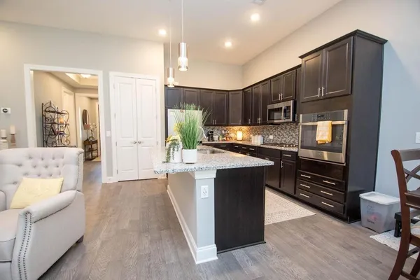 a kitchen with stainless steel appliances kitchen island granite countertop a refrigerator and a stove top oven