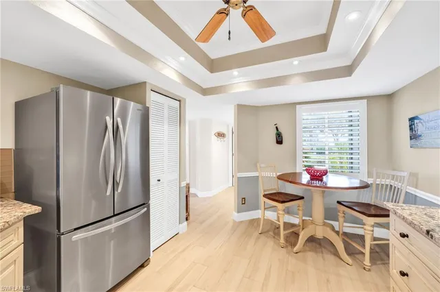 a kitchen with stainless steel appliances granite countertop a refrigerator a stove a dining table and chairs with wooden floor