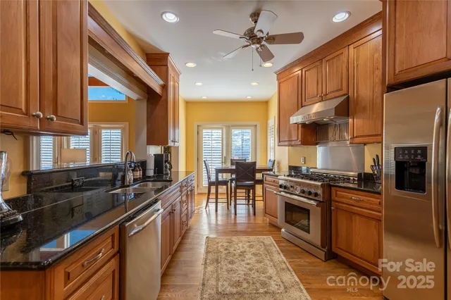 a kitchen with stainless steel appliances granite countertop a stove a sink dishwasher and a microwave oven with white cabinets