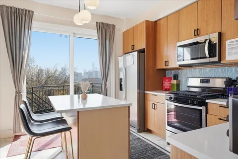 a kitchen with stainless steel appliances a stove a refrigerator and a table chair