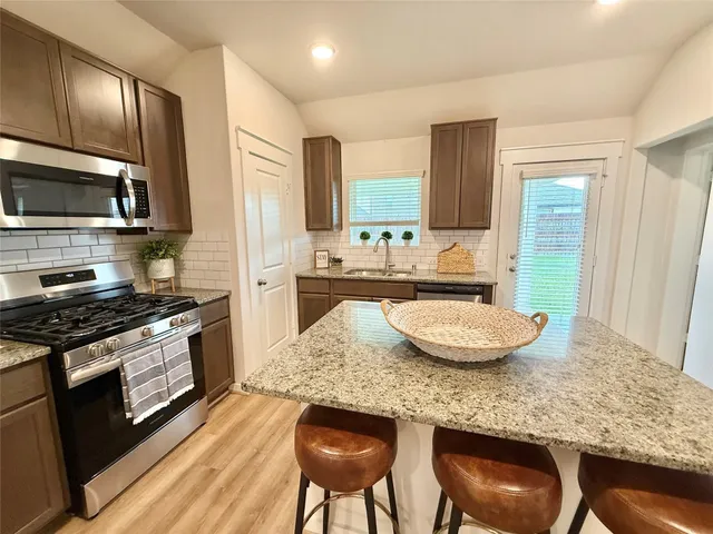 a kitchen with kitchen island granite countertop wooden cabinets and a stove