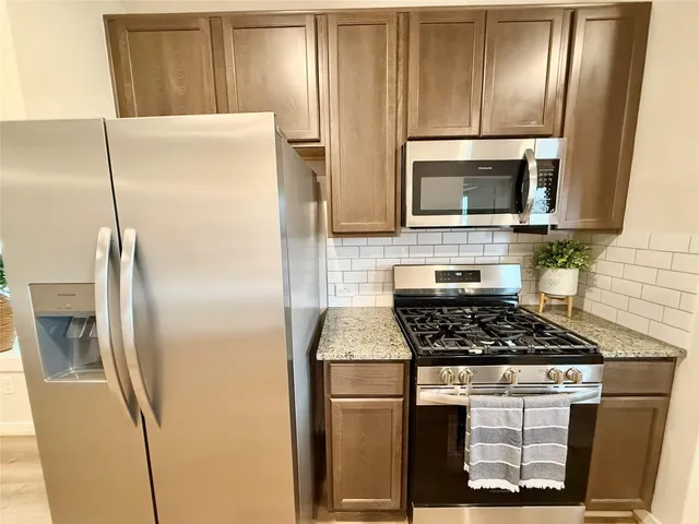 a kitchen with stainless steel appliances granite countertop a refrigerator a stove and a sink