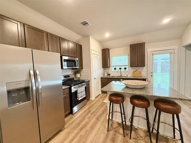 a kitchen with stainless steel appliances kitchen island granite countertop a refrigerator a stove a sink dishwasher with a dining table and chairs