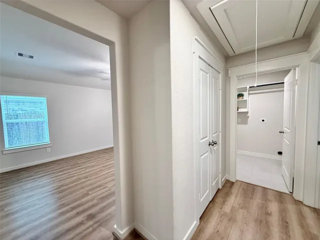 a view of a hallway with wooden floor and closet area