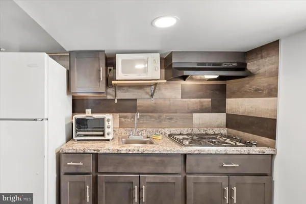 a kitchen with granite countertop a sink stove and refrigerator