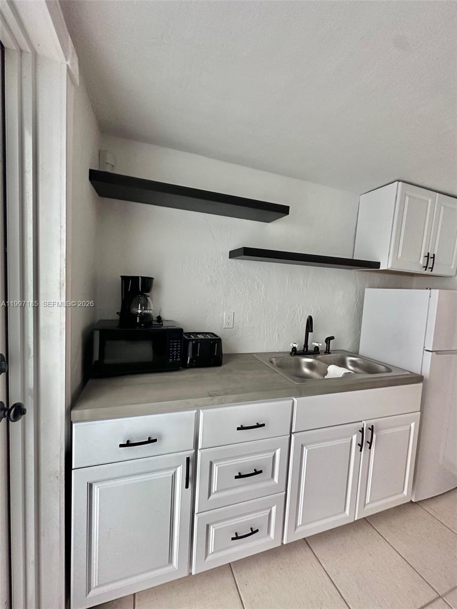 1375 Northwest 84th Terrace, Unit A Miami, FL 33147 - Photo 3 of 11 a kitchen with white cabinets and appliances