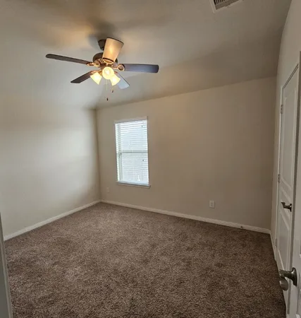 an empty room with windows and fan