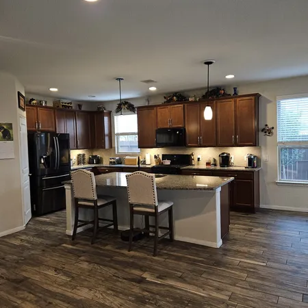 a kitchen with stainless steel appliances kitchen island granite countertop a refrigerator a stove a sink a dining table and chairs