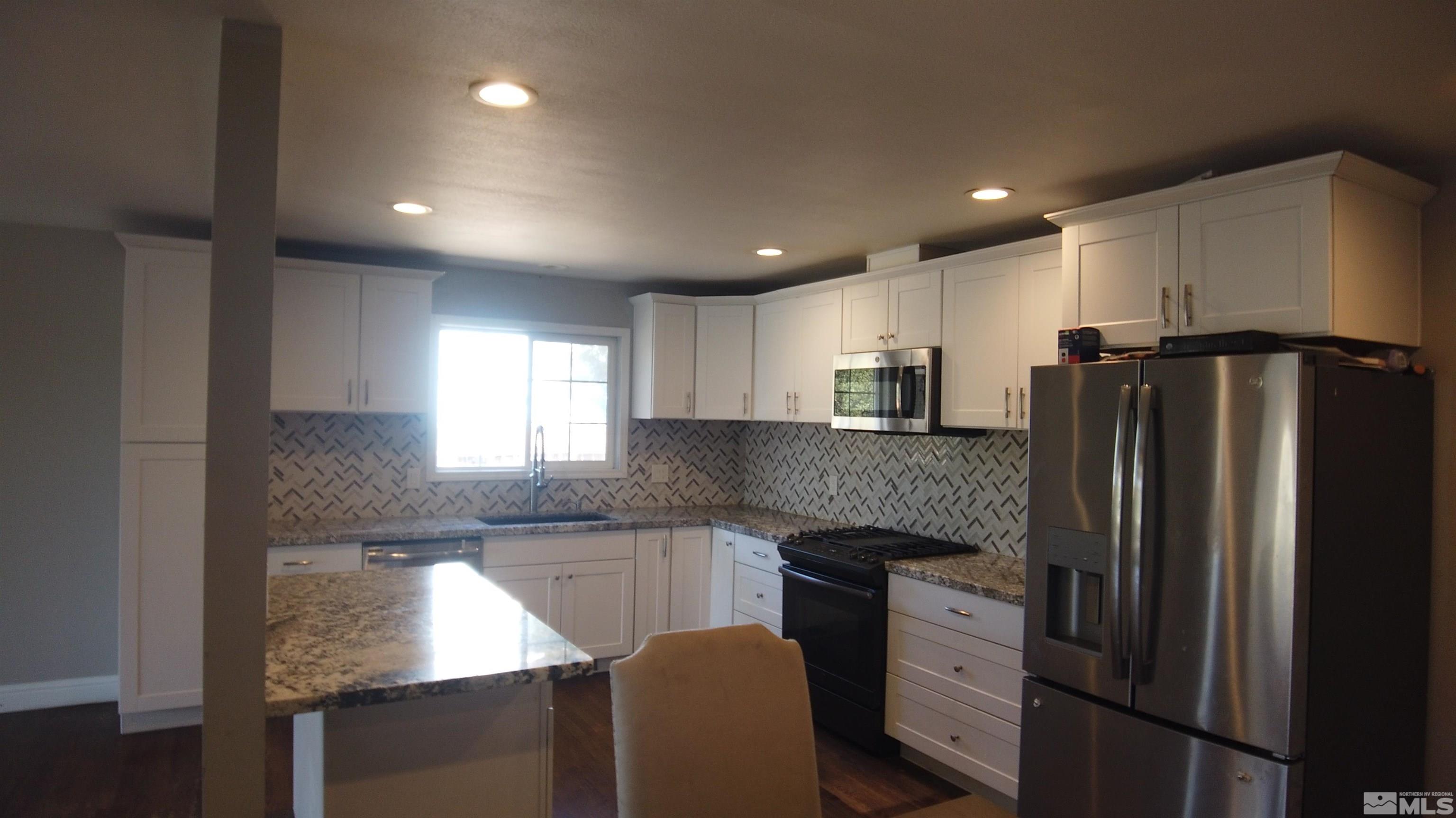 2650 Apollo Way Reno, NV 89503 - Photo 24 of 36 a kitchen with granite countertop white cabinets and stainless steel appliances