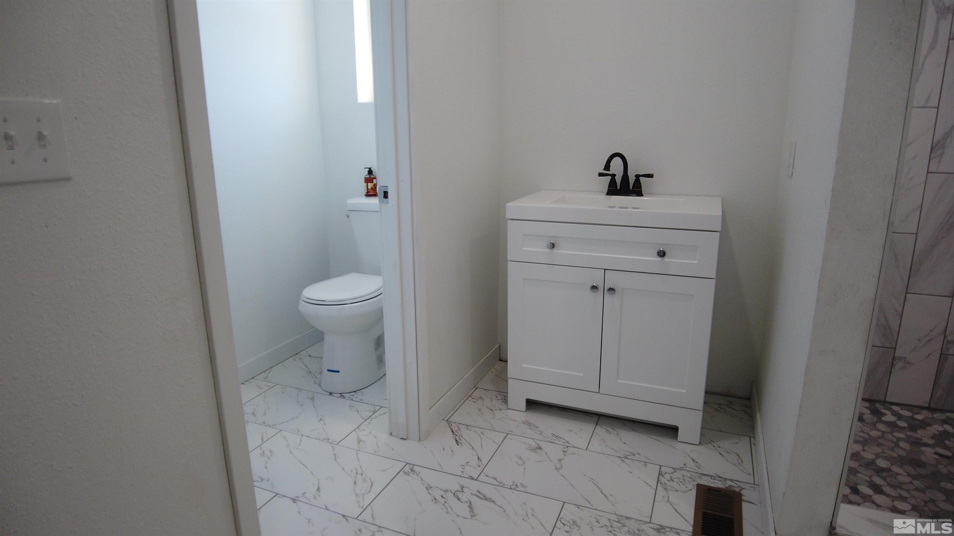 2650 Apollo Way Reno, NV 89503 - Photo 32 of 36 a bathroom with a sink a toilet and a mirror