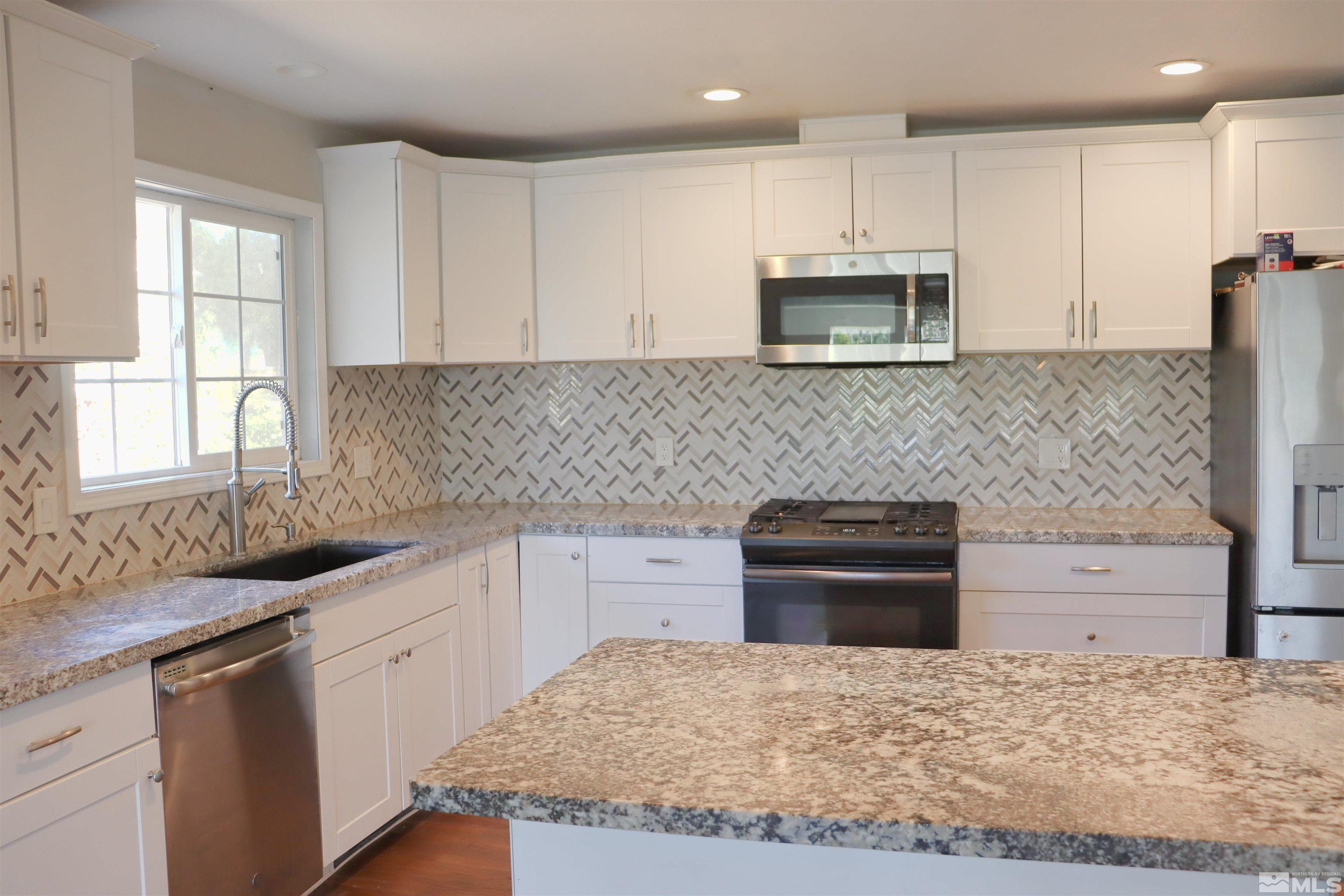 2650 Apollo Way Reno, NV 89503 - Photo 4 of 36 a kitchen with granite countertop white cabinets and stainless steel appliances