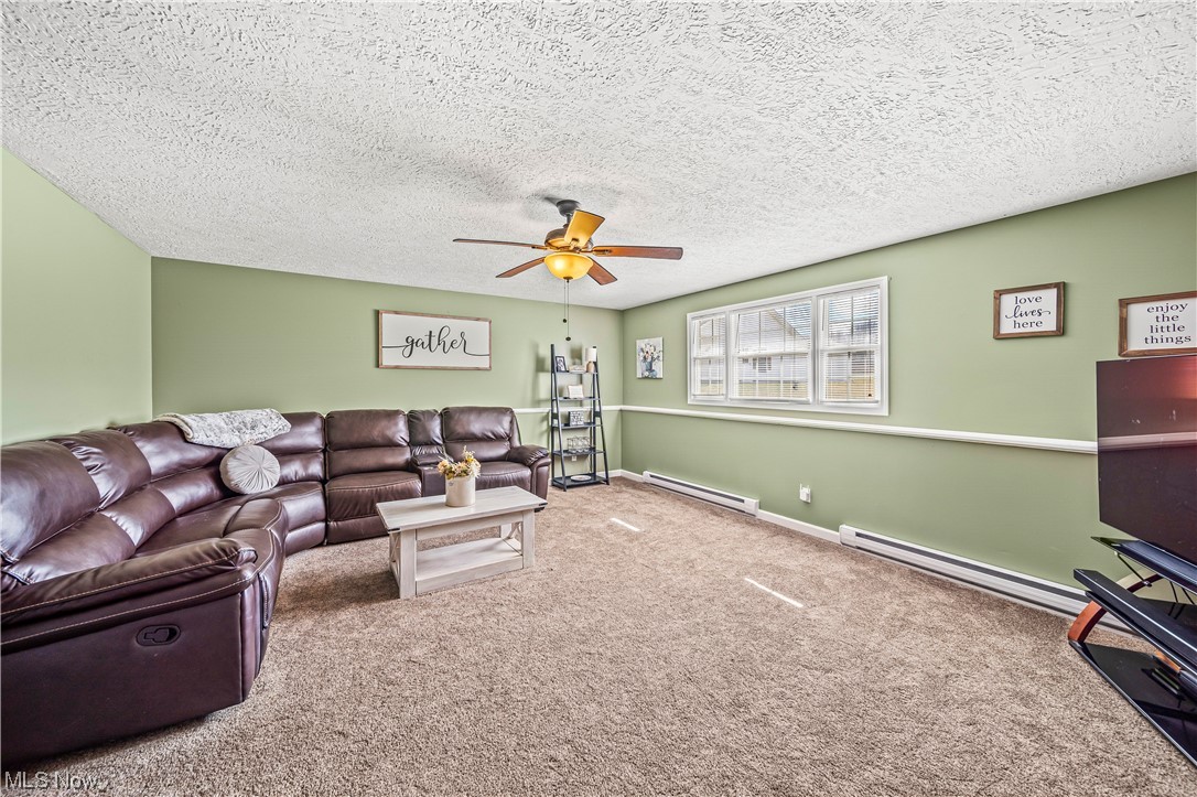 7290 Turner Road Pierpont, OH 44082 - Photo 19 of 36 Carpeted living room featuring a baseboard radiator, a textured ceiling, and ceiling fan