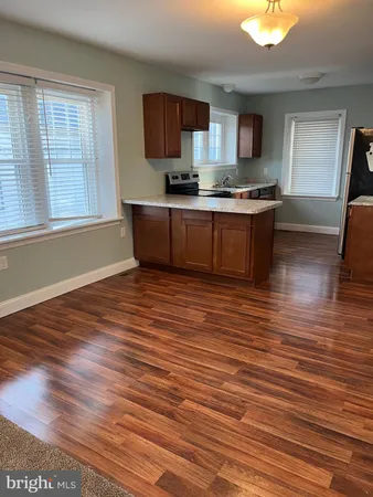 a kitchen with stainless steel appliances granite countertop a sink wooden cabinets and a wooden floor
