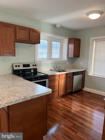 a kitchen with granite countertop a sink a stove wooden floor and cabinets