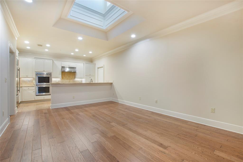 6425 Bandera Avenue, Unit 2D Dallas, TX 75225 - Photo 3 of 8 Unfurnished living room with light hardwood / wood-style flooring, a tray ceiling, ornamental molding, and a skylight