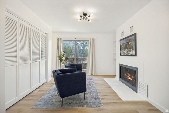 1723 Albury Road Sandy, UT 84092 - Photo 11 of 23 Living area featuring wood-finish flooring, a contemporary ceiling fixture, and a fireplace with a white tile hearth