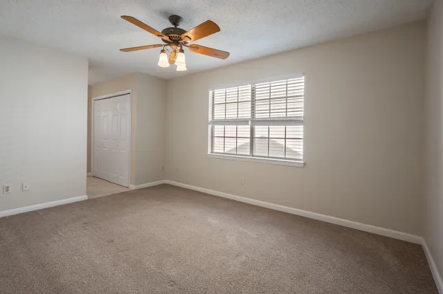 an empty room with windows and fan