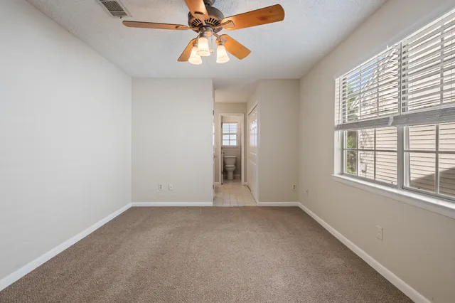an empty room with windows and fan