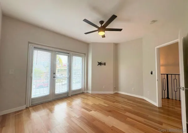 an empty room with wooden floor fan and windows