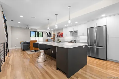 a kitchen with stainless steel appliances kitchen island granite countertop a refrigerator a sink dishwasher and a stove with wooden floor