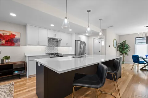 a kitchen with a sink a stove a dining table and chairs with wooden floor