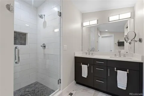 a bathroom with a double vanity sink mirror and shower