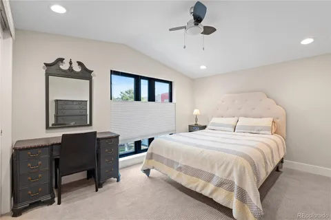 a bedroom with a bed a desk and chair with a mirror