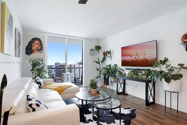 a living room with furniture a potted plant and a large window