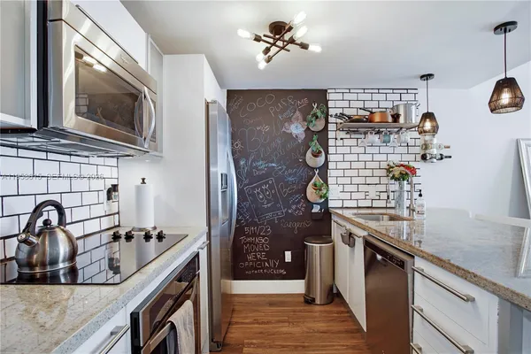a kitchen with stainless steel appliances granite countertop a sink a stove and wooden cabinets