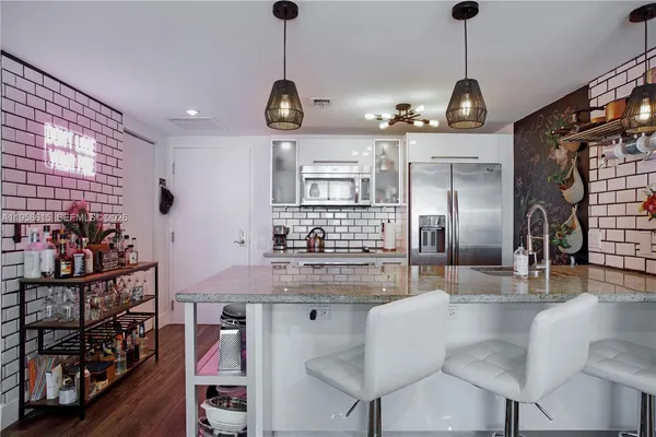 a kitchen with stainless steel appliances granite countertop a sink a refrigerator and chairs