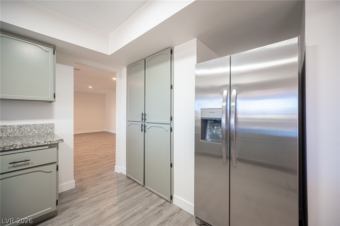 7041 North Decatur Boulevard Las Vegas, NV 89131 - Photo 8 of 33 A streamlined kitchen hallway features a spacious refrigerator and ample pantry storage, leading to an open living area.
