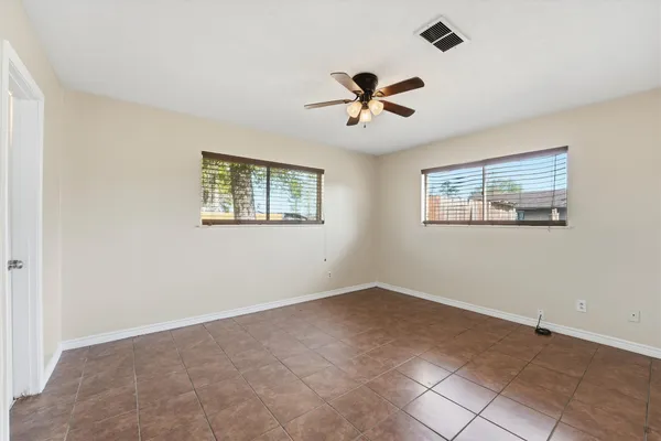 a view of a big room with windows and chandelier fan