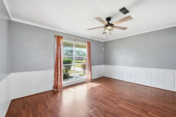 an empty room with wooden floor fan and windows