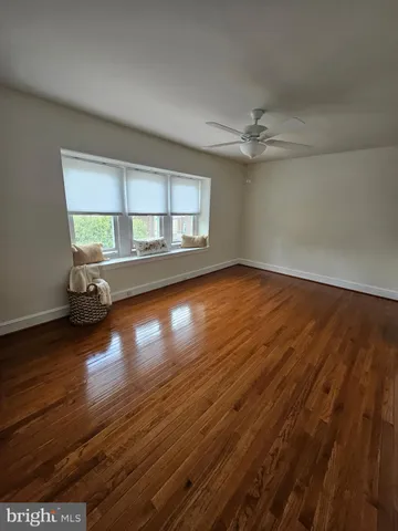 an empty room with wooden floor chandelier and windows