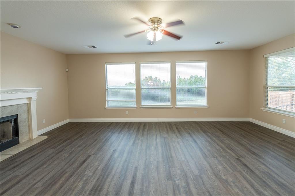 12017 Springs Head Loop Austin, TX 78717 - Photo 6 of 25 Ample natural light illuminates the spacious living area with resilient plank flooring and a cozy fireplace.