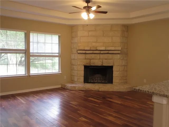 a view of a livingroom with wooden floor a fireplace and windows