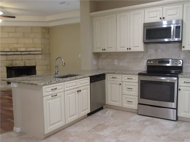 a kitchen with stainless steel appliances granite countertop white cabinets a stove a sink and dishwasher