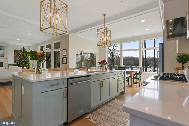 a open kitchen with stainless steel appliances granite countertop a sink dishwasher a stove and a dining table with wooden floor