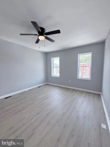 an empty room with wooden floor ceiling fan and windows