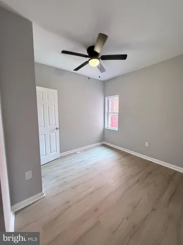 an empty room with wooden floor ceiling fan and windows