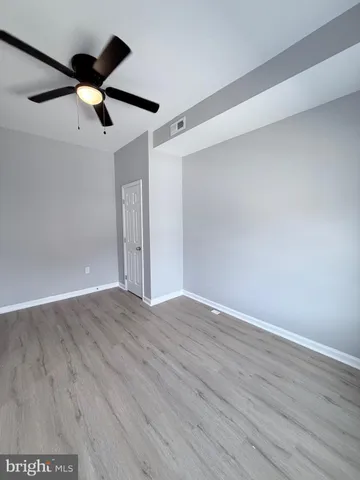 an empty room with wooden floor ceiling fan and window