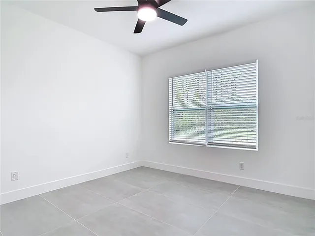 an empty room with a window and a fan