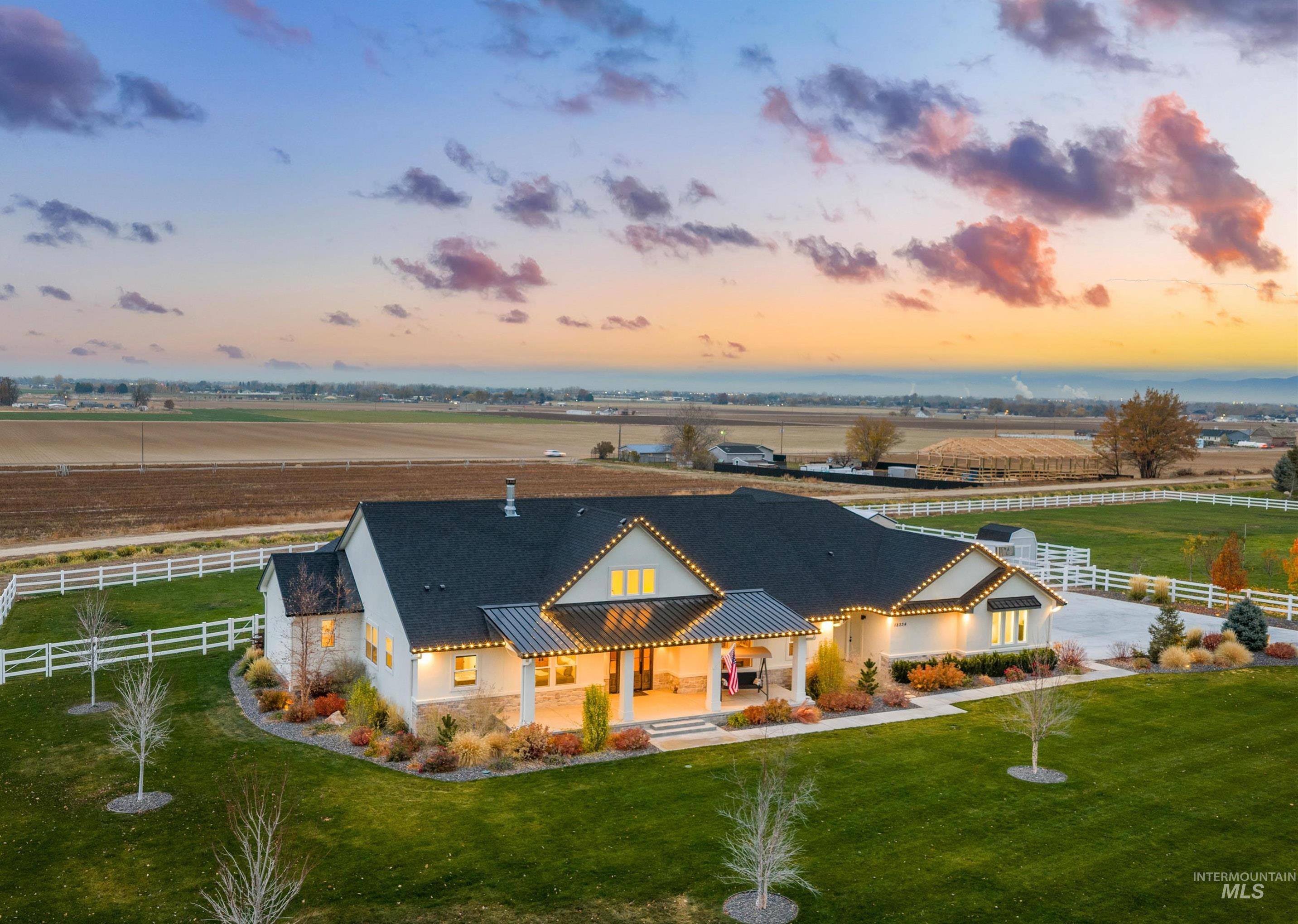 Rear view of property with covered porch, a view of countryside, and stucco siding
