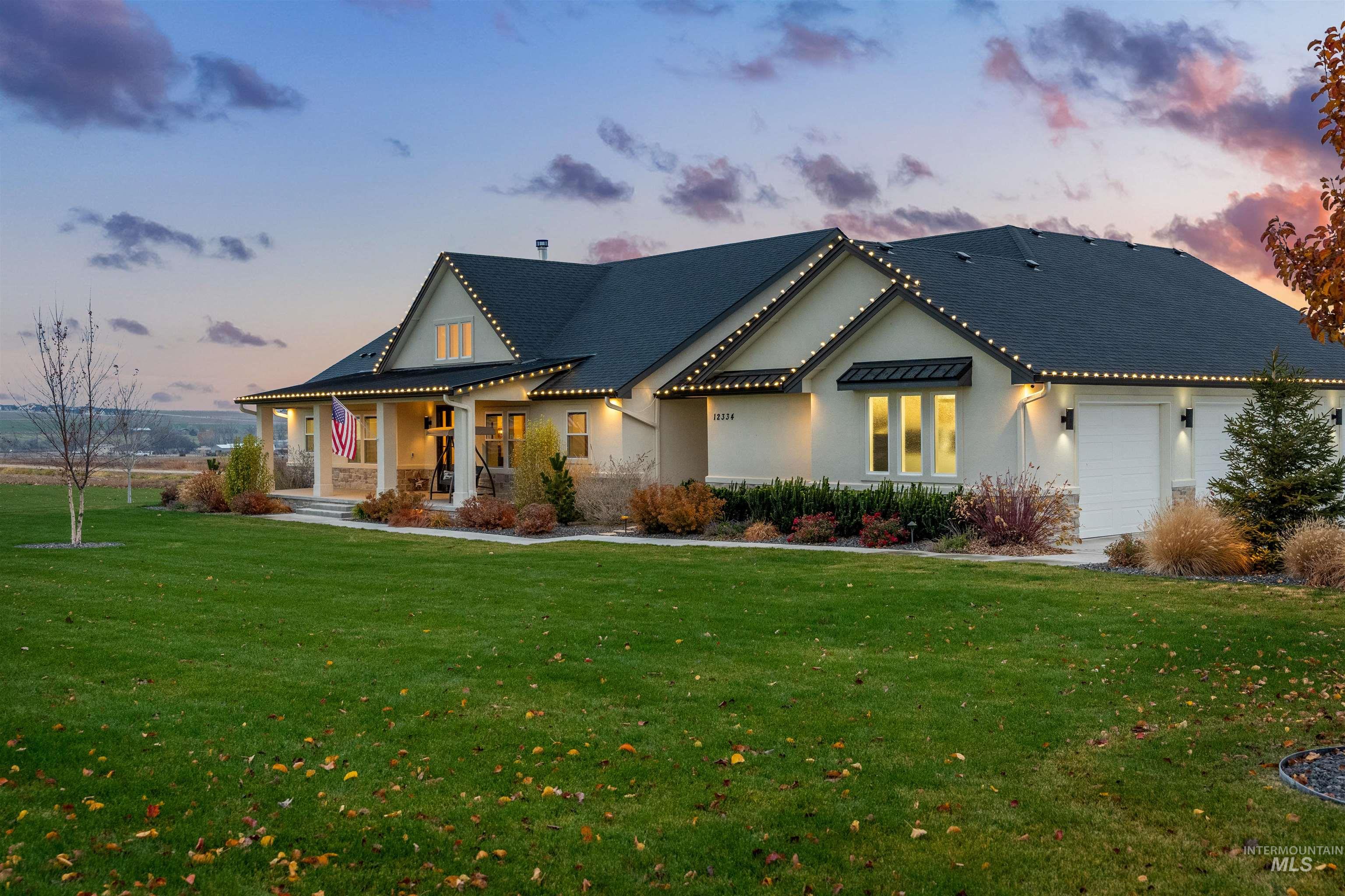12334 Rivendell Court Nampa, ID 83686 - Photo 4 of 50 View of front of house featuring a porch, a lawn, a garage, and stucco siding